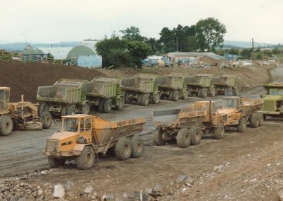 Construction vehicles parked up near Naid y March with site workshops and offices in the background